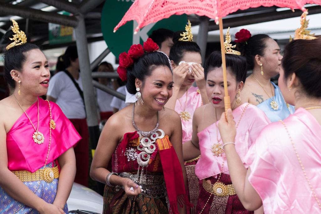 Dancers in vibrant traditional pink and red dresses at a Thai festival