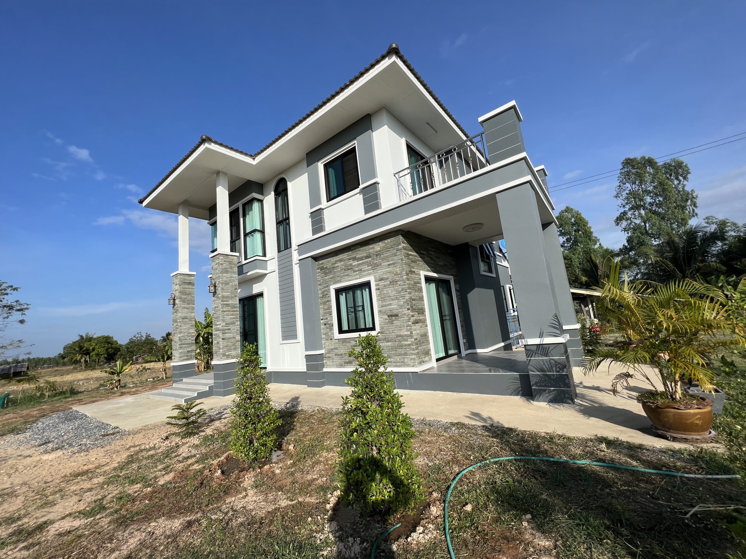 Modern two-story farmhouse in Thailand with white and gray exterior