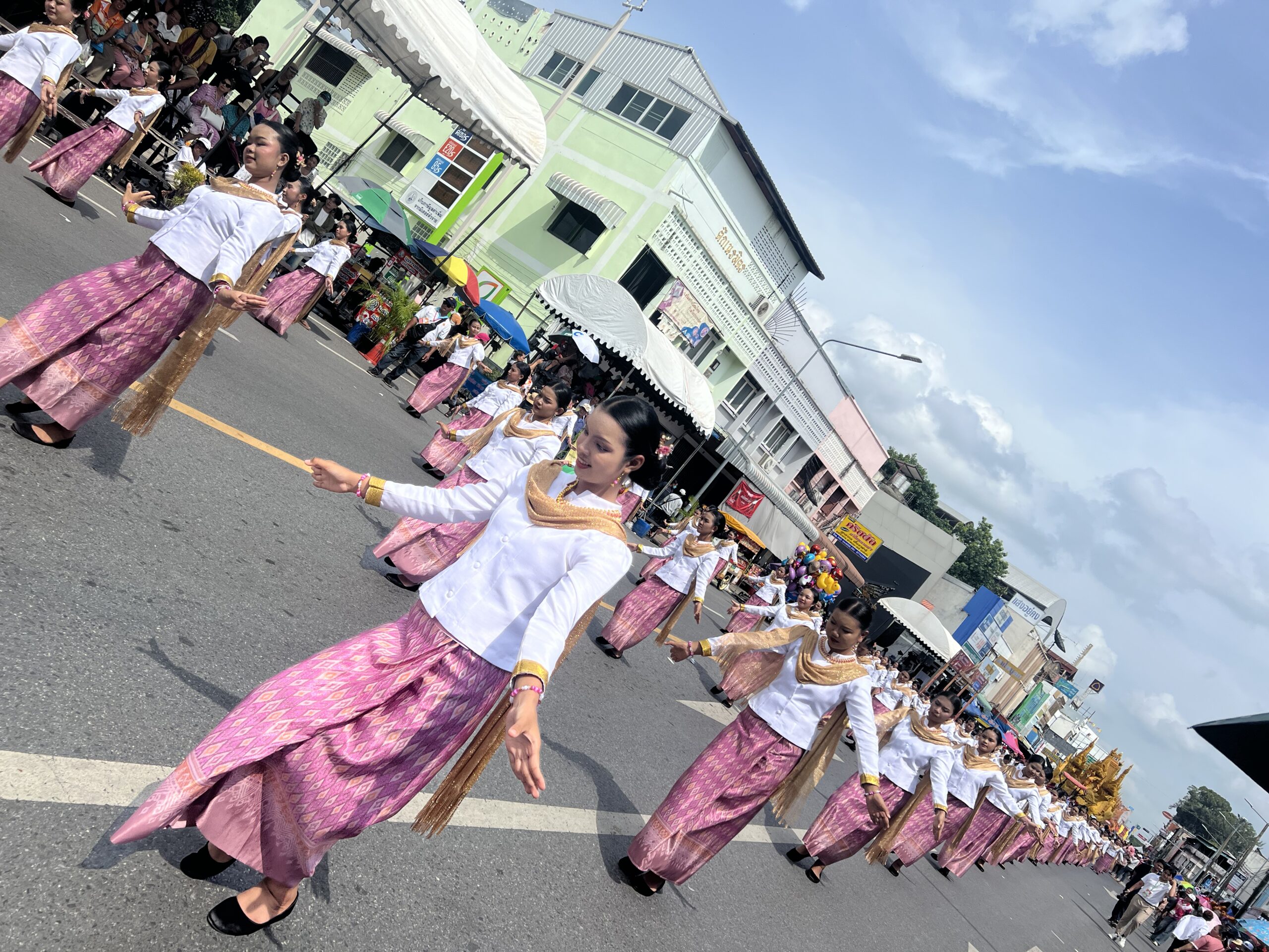 Thai dancers in white and pink in a parade at Ubon Candle Festival