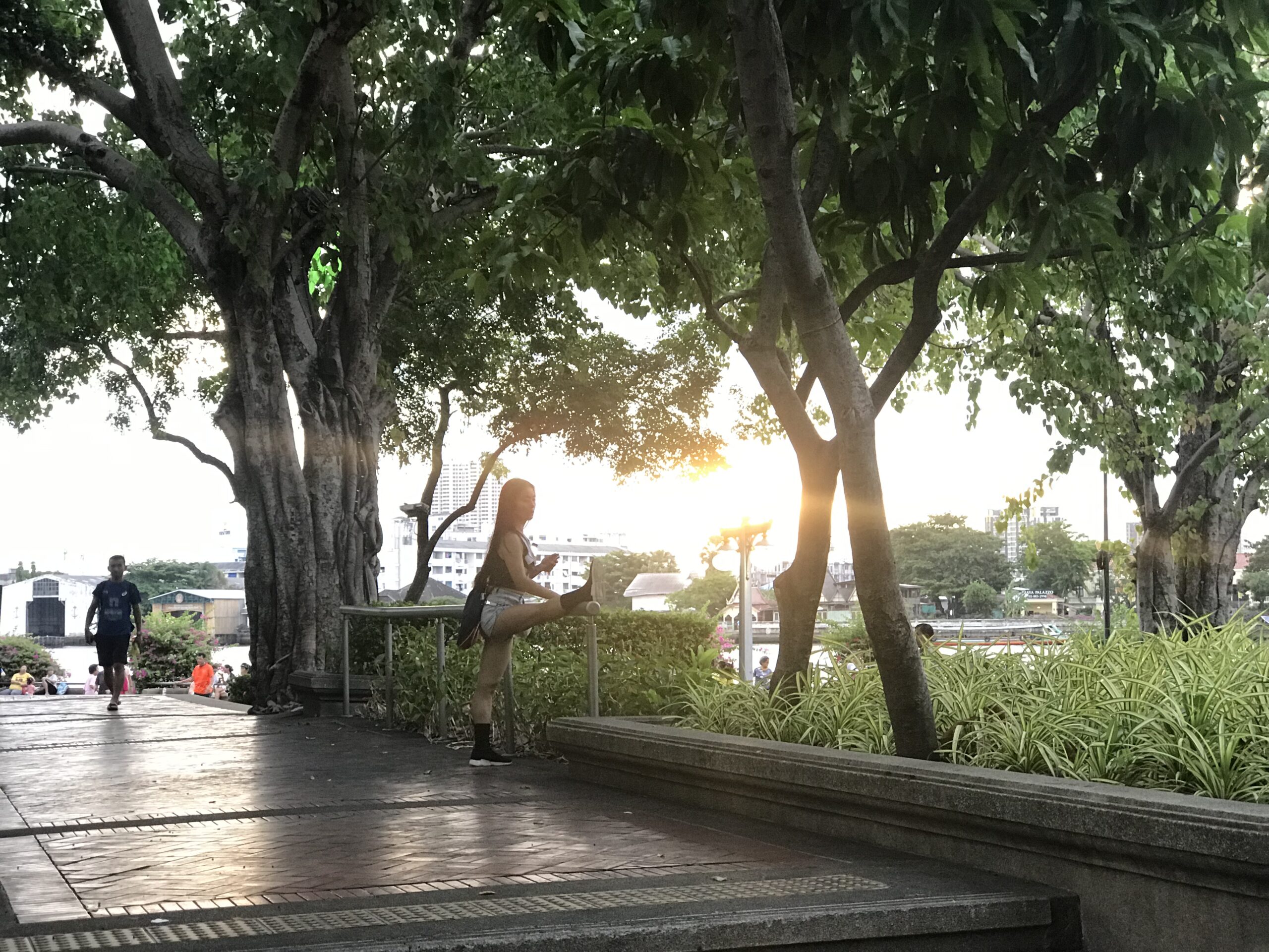 Thai woman stretching on a park fitness pole at sunset in Isan