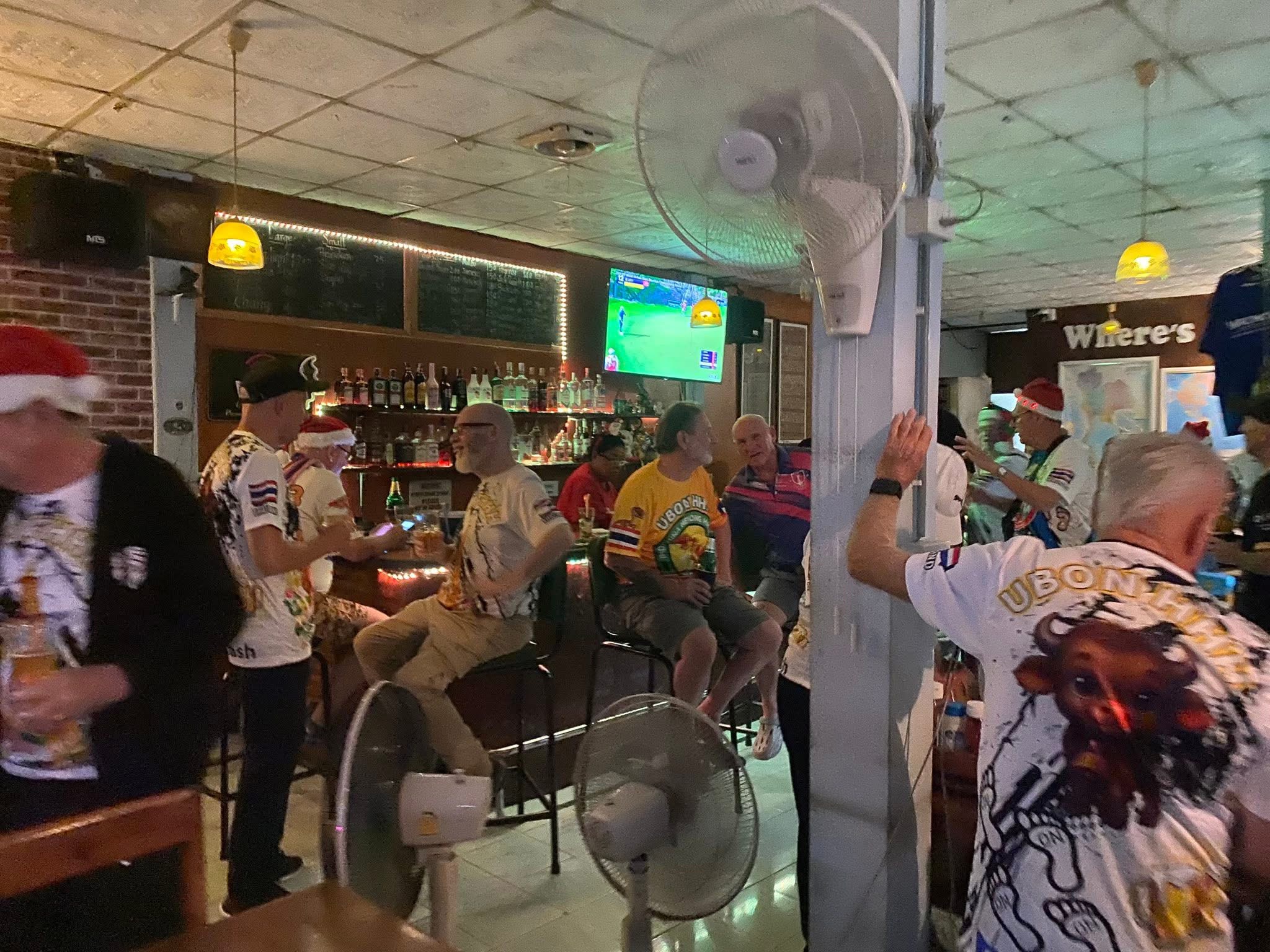 Men enjoying drinks and watching football at a local bar in Ubon
