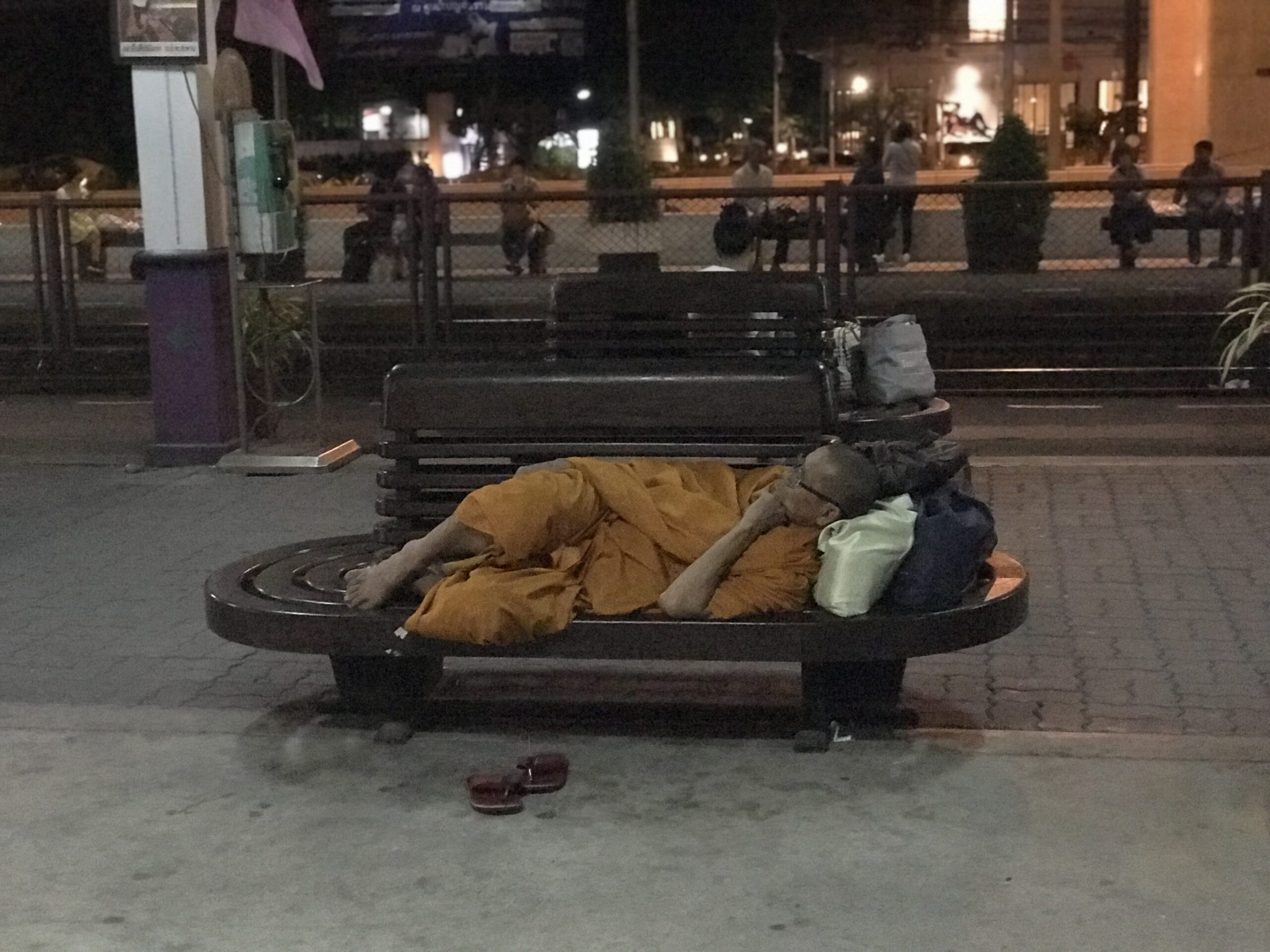 Thai monk resting on a bench outside a railway station