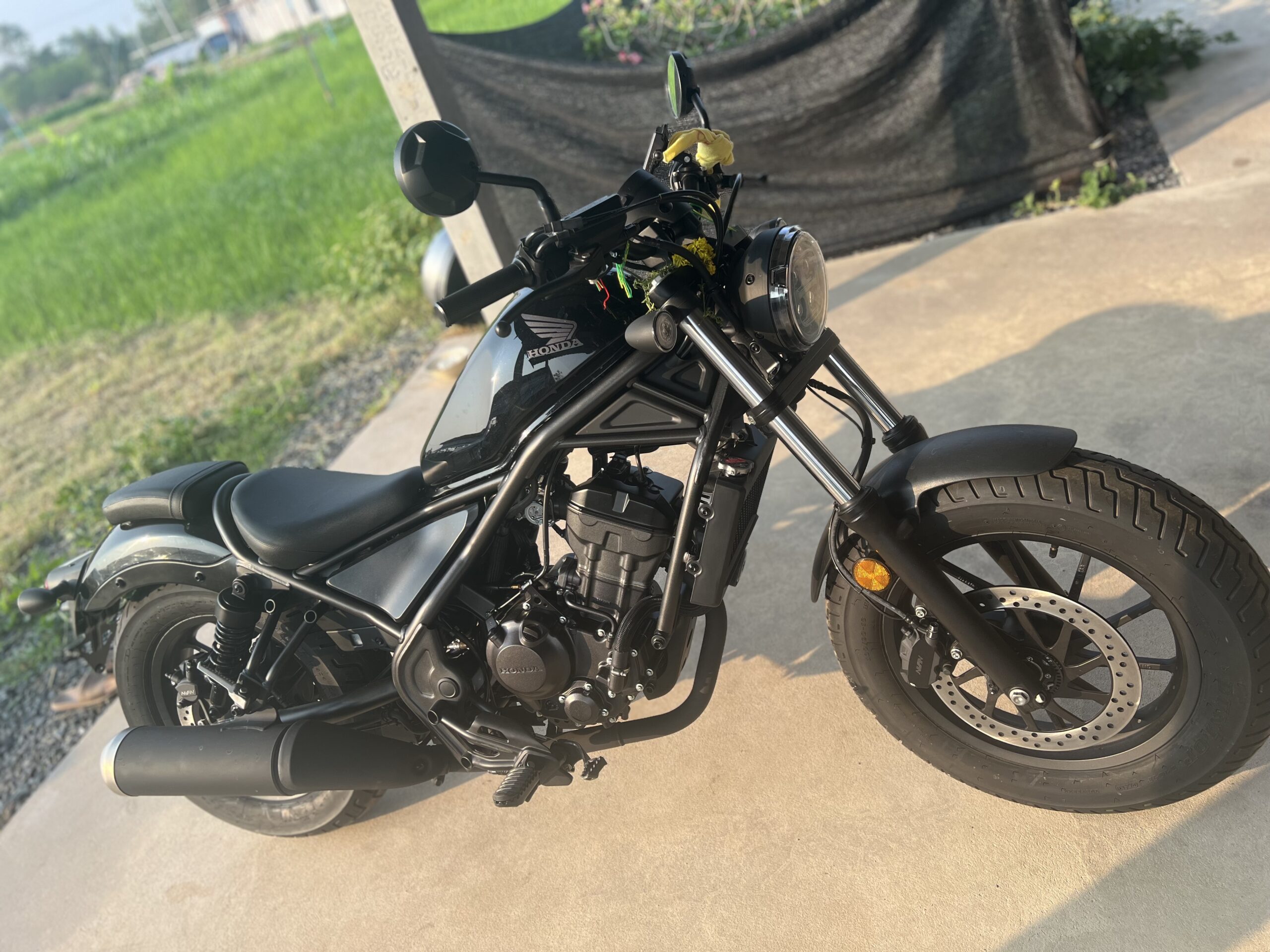 Honda Rebel 250 motorcycle parked outside farm garage in Isan