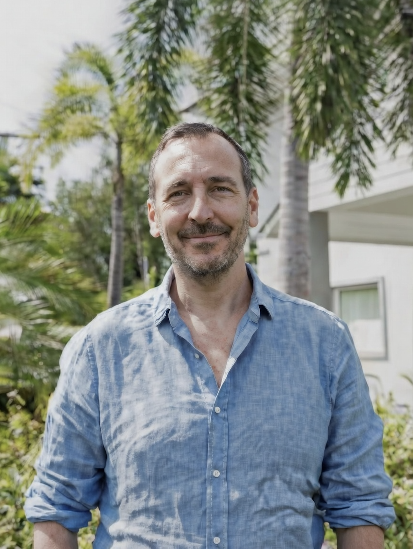 Steve Radley, counsellor, standing relaxed in blue shirt among palm trees